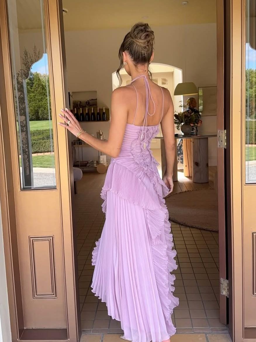 Sleeveless maxi dress for wedding guests, featuring elegant asymmetric pleats and a flowing skirt.
