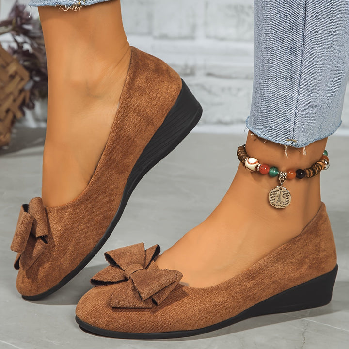 Comfortable and stylish slip-on wedge shoes for women, featuring a prominent bow detail.