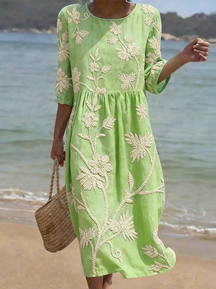 Full-length view of a women's floral embroidered midi dress with three-quarter sleeves, showcasing its elegant design.