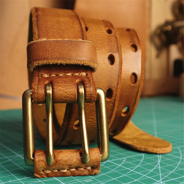 Detailed view of a mens full-grain leather belt, highlighting the texture and double-prong buckle.