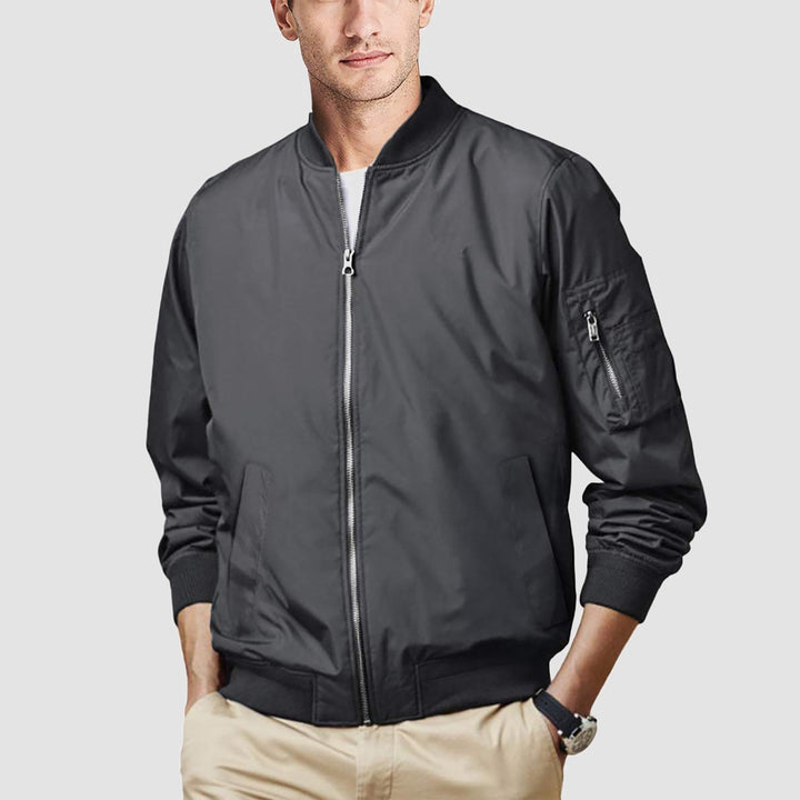 Man checking his phone, wearing a modern men's bomber jacket, casual everyday scene