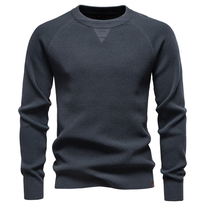 Stack of folded men's waffle knit pullover sweaters in various colors, ready for display.