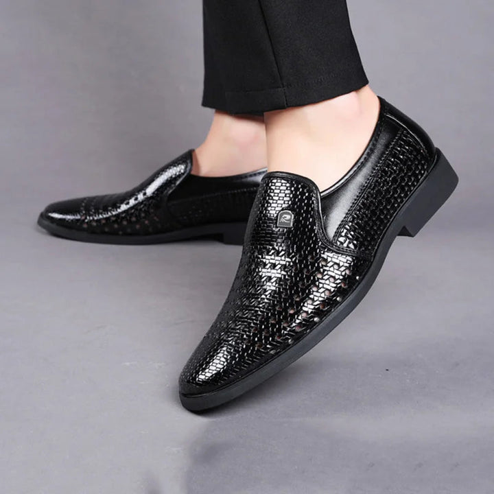 Pair of black men's woven leather slip-on loafers, showcasing sleek design & durable construction.
