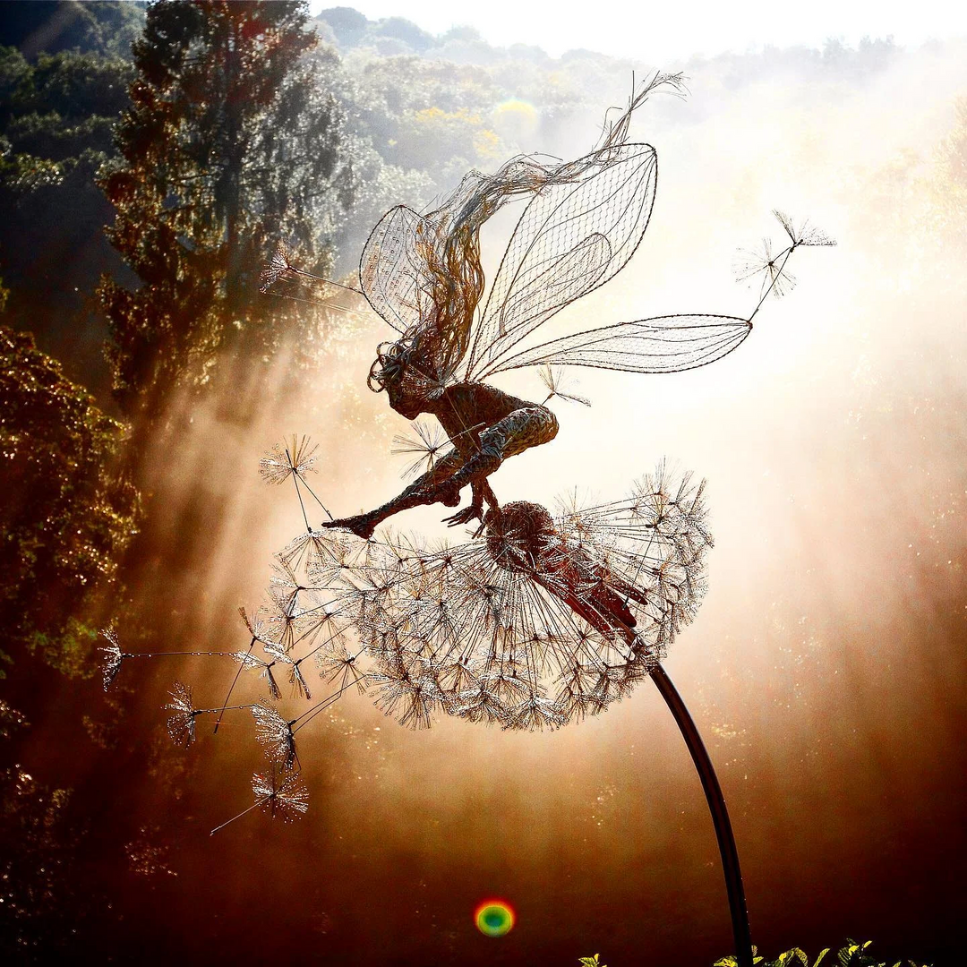 Whimsical metal fairy with lifelike dandelion stakes, ideal for enchanting garden decor, adding magic to outdoor spaces.