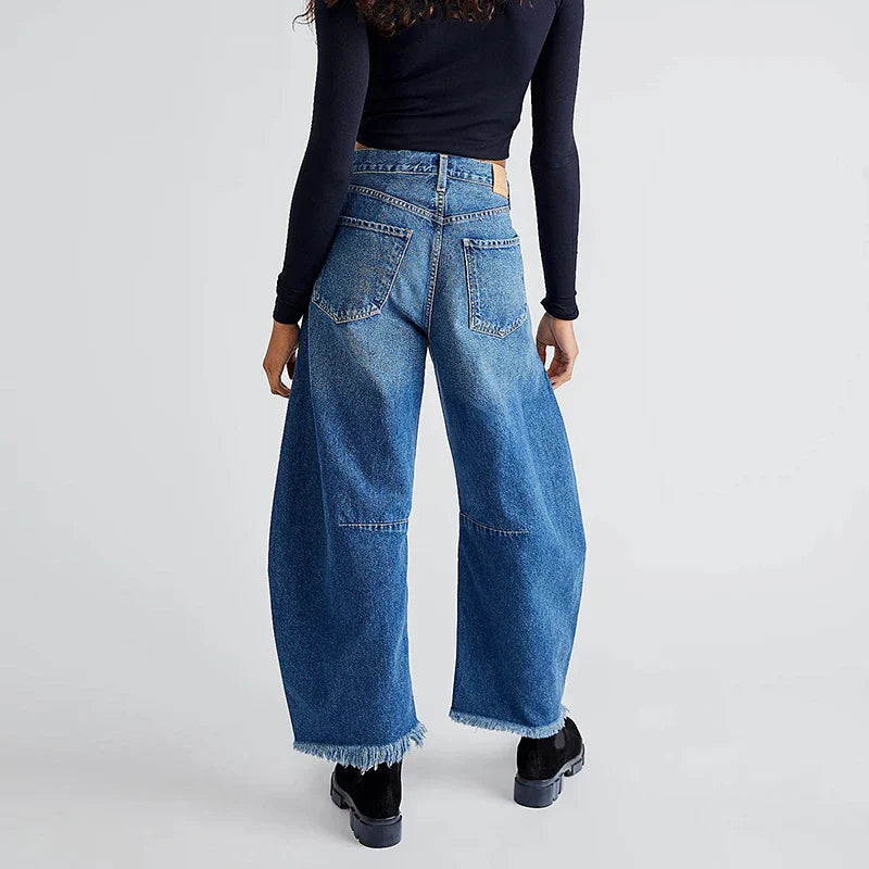 Back view of women's organic loose fit high-rise jeans, straight leg, and unique frayed hem detail.